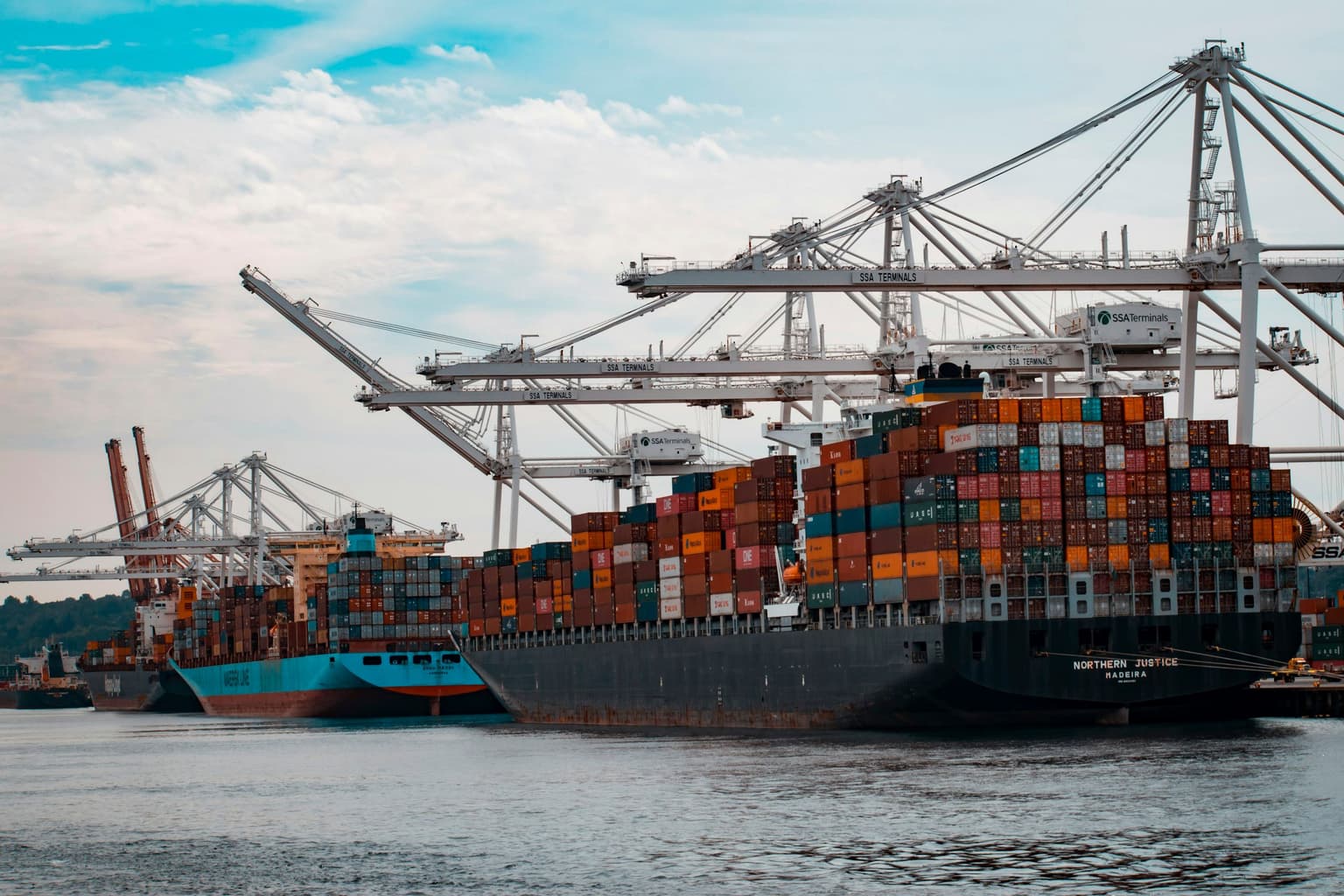 Container ship berthed beneath port cranes